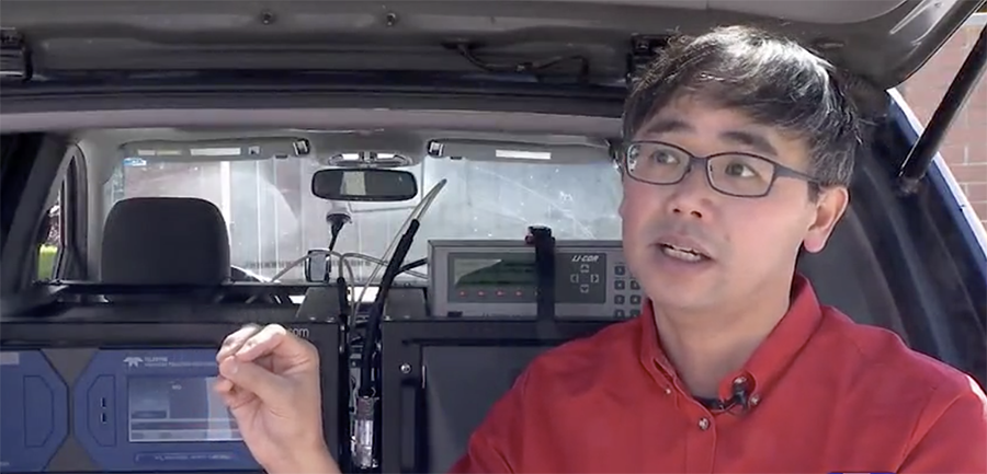 John Lin sits in front of air monitors mounted in a vehicle